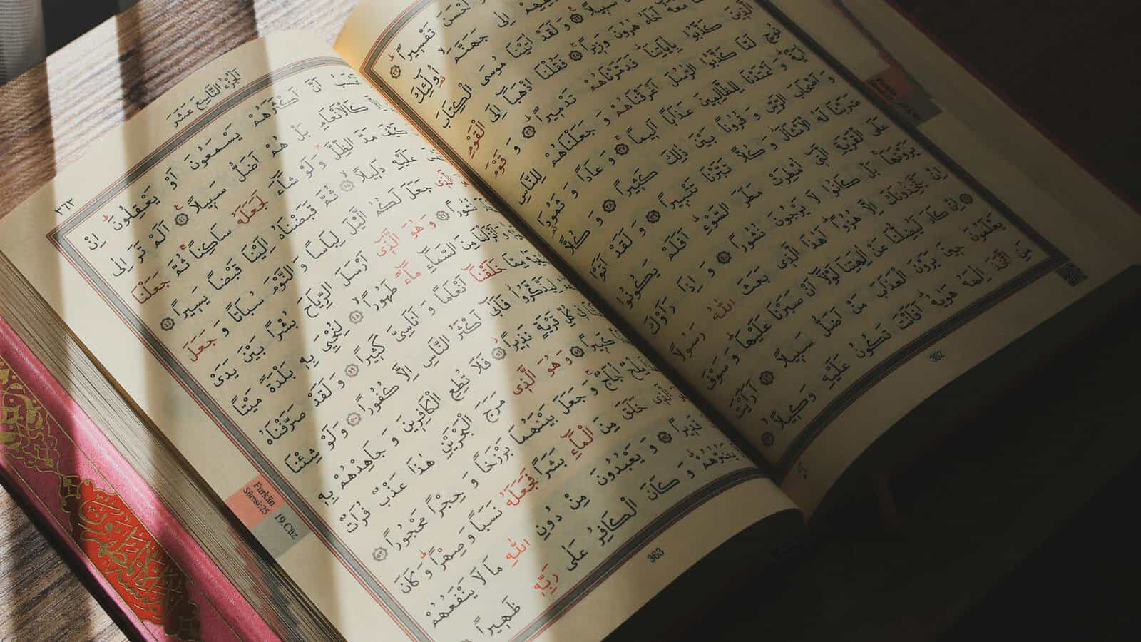 Open tajweed-coded Mushaf with color-marked Arabic calligraphy illuminated by natural sunlight