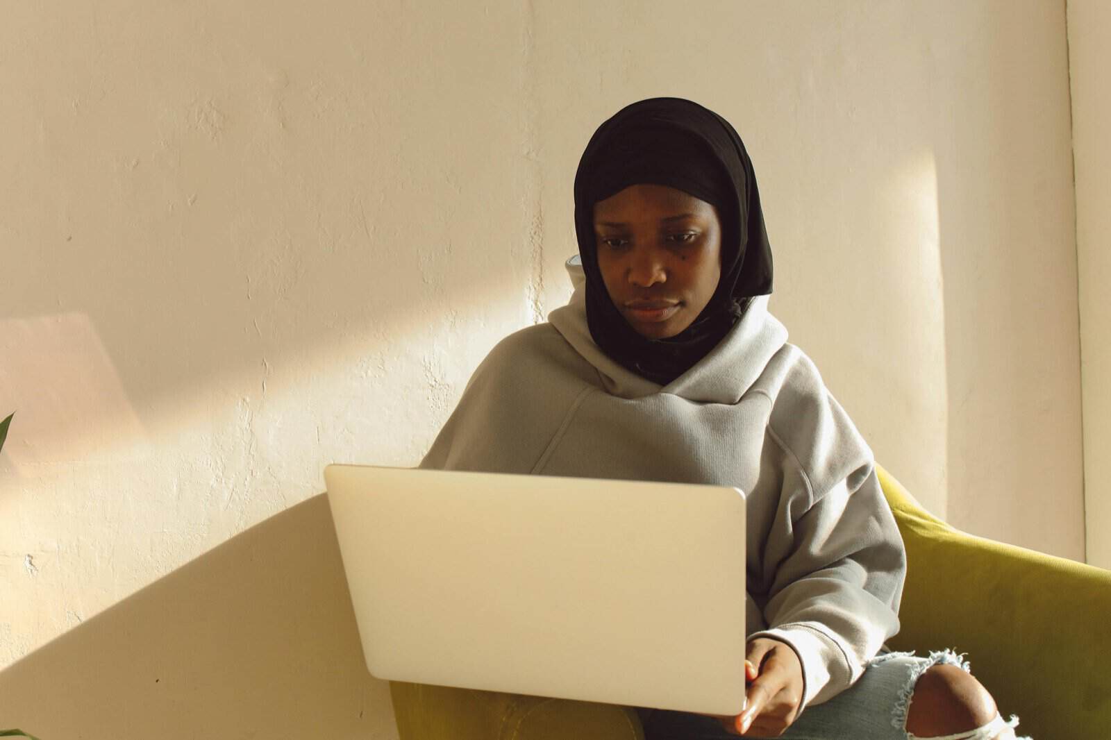 Muslim woman in hijab learning to read the Quran online with a laptop at home