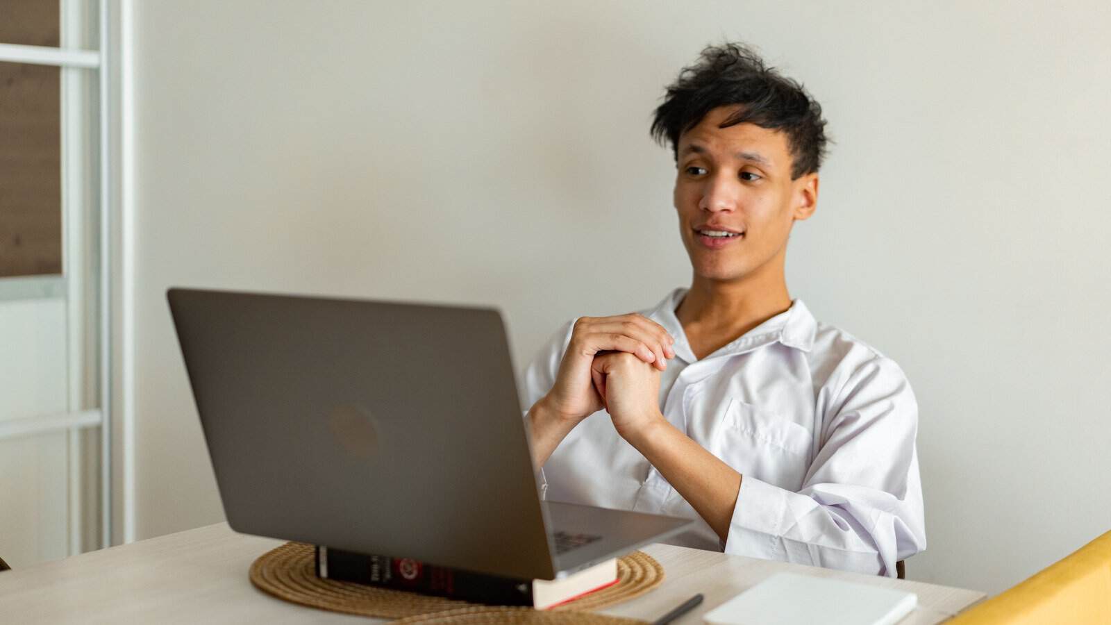 A student speaking to his teacher during an online Quran lesson on a laptop at home