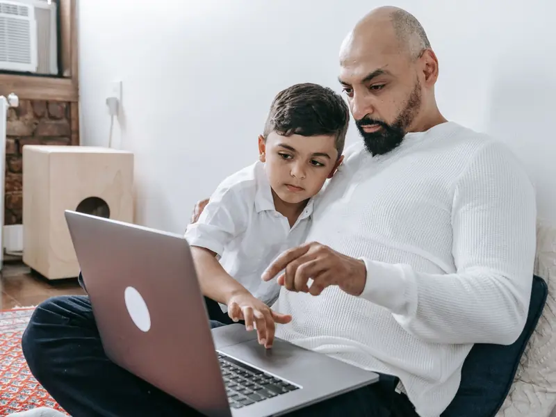 A father and his young son looking at a laptop together at home